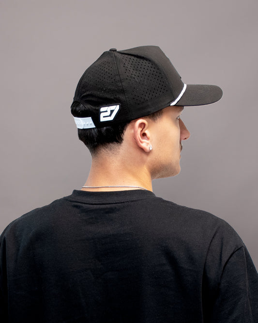 Rückansicht der schwarzen SL27 Performance Cap Gummilabel der Nummer 27 und schwarzem Mesh-Einsatz, vor hellem Hintergrund fotografiert.
