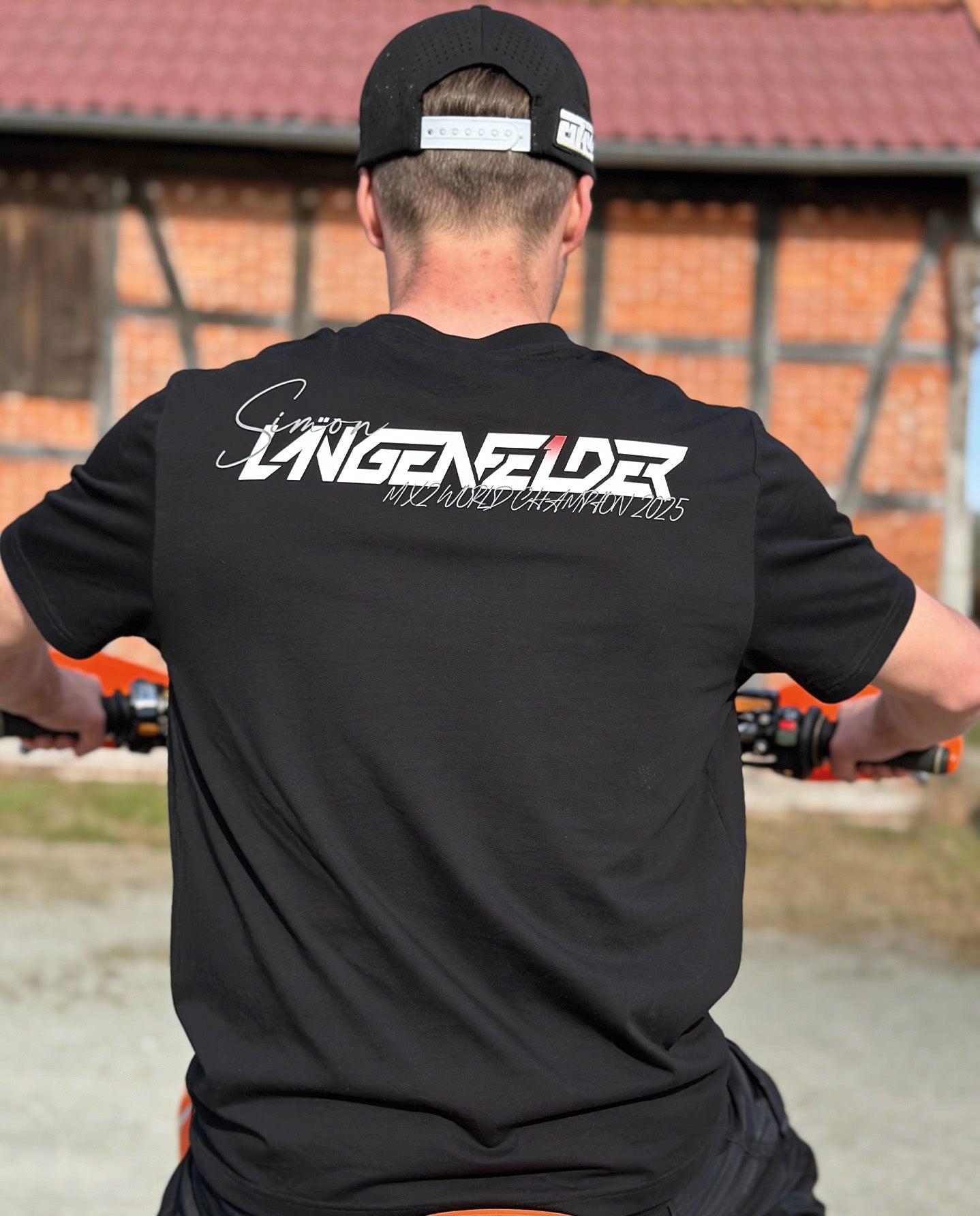 Rückansicht eines schwarzen SL27 „HomeGP Germany“ T-Shirts mit großem „Simon Längenfelder MX2 World Champion 2025“-Rückenprint in Weiß auf schwarzem Hintergrund.