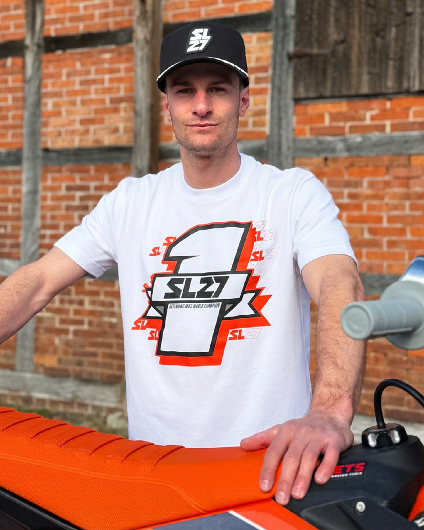 Weißes SL27 T-Shirt „Number One“ mit großem Nummer-1-Frontprint und SL27-Logo, getragen von Simon Längenfelder am Motocross-Bike.